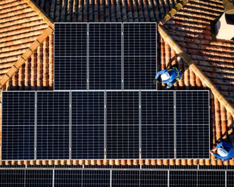 Aerial view of Two workers installing solar panels on a house roof.