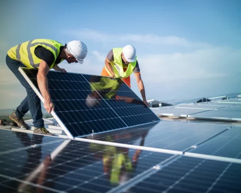 Team of two engineers installing solar panels on roof.
