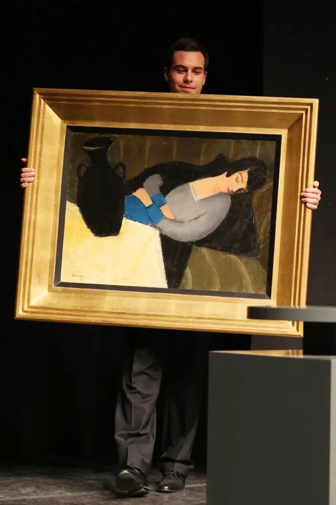 A staff member of the gallery carries the painting "Sleeping woman with black vase" by Hungarian artist Robert Bereny during an auction at the Judit Virag Gallery in Budapest on December 13, 2014. A long-lost avant-garde painting went under the auction hammer Saturday in Hungary, after a sharp-eyed art historian rediscovered it being used as a prop in the Hollywood film "Stuart Little".