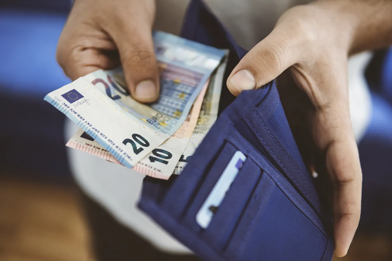 A man takes euro banknotes from his wallet.