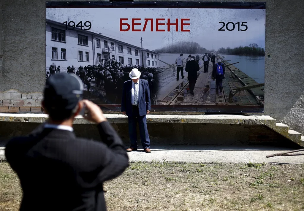 A man poses for a picture in front of a poster placed outside the crumbling building of a communist-era prison built on the site of former labour camp Belene, on the Danube island of Persin, Bulgaria May 30, 2015. Several hundred survivors, relatives and locals gathered on Saturday to commemorate the victims of the Communist regime in Bulgaria. Thousands of "enemies of the regime" were imprisoned in 1949-59 in Belene concentration camp. Bulgaria spent 45 years under the one-party Communist rule which collapsed in November 10, 1989.