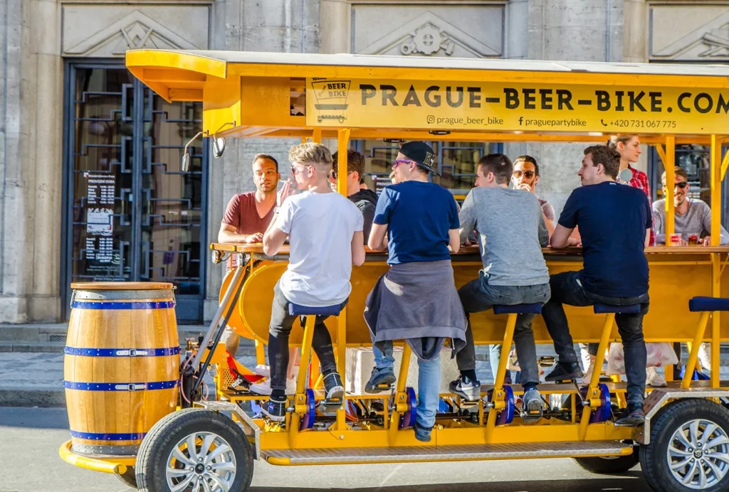 Yellow beer bike serving as guided tour while drinking beer in going away on downtown Prague street during day of springtime.