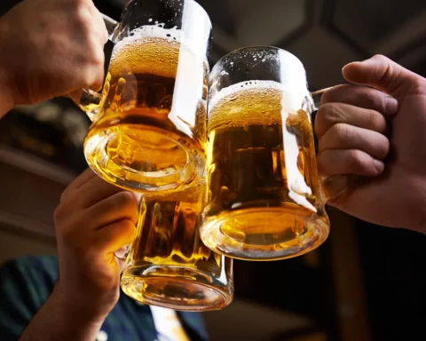Hands of three men toasting with beer