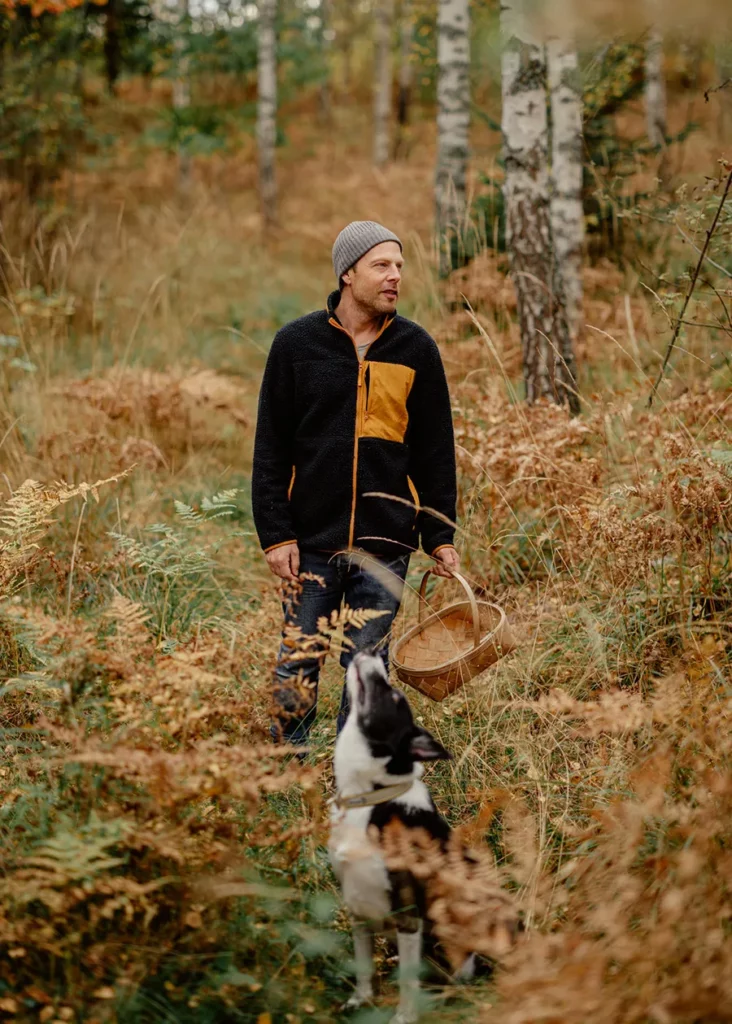 Man picking mushrooms in the woods. Photo taken outdoors in atumn in forest.