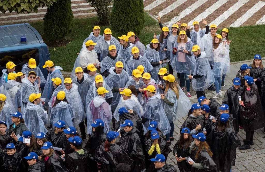 People in various raincoats and baseball caps in yellow and blue.