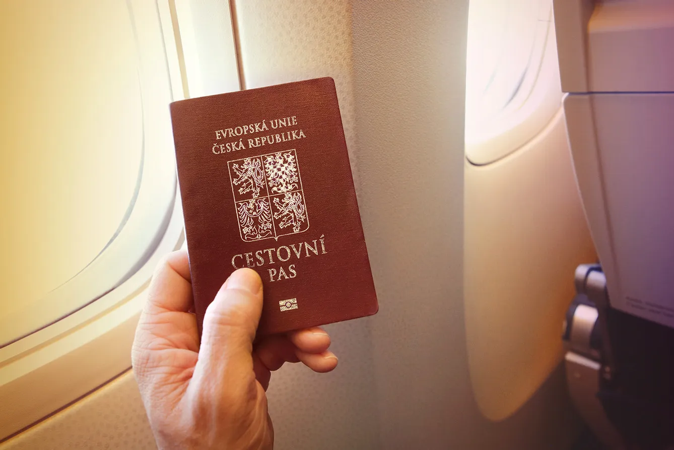 Detail of passenger's hand holding passport of the Czech Republic on the airplane.