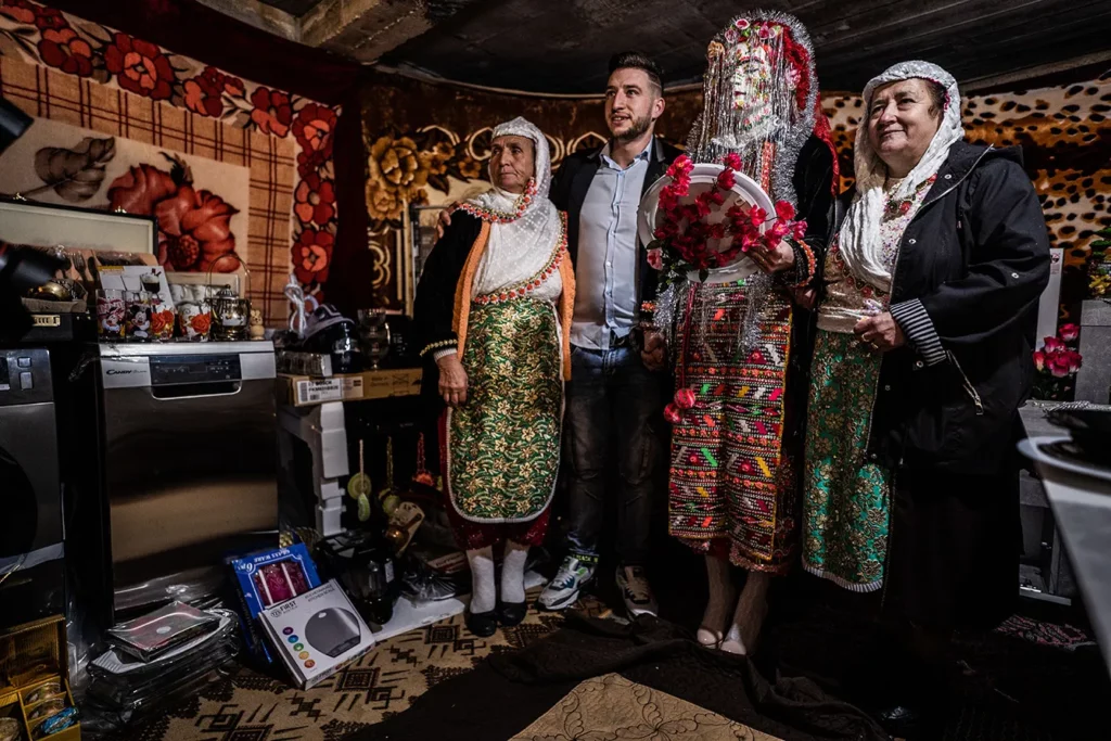 Groom Shaban Kiselov, (L) and the bride Nefie Eminkova, (R) pose for a picture with friends in front of the dowry on their wedding day on January 9, 2022 in Ribnovo, Bulgaria. Bulgarian Pomaks from Ribnovo have their unique weddings only in the winter. The weddings continue two or three days and the bride must marry with her eyes closed and her face painted white with shining sequins.